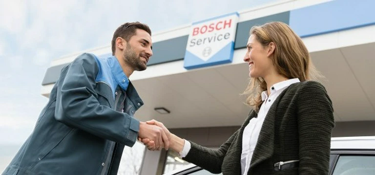 Klient i&nbsp;pracownik serwisu Bosch podający sobie rękę przed warsztatem samochodowym